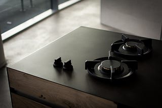 An unfortunate ‘sleek’ stovetop design with two burners lined atop of each other with two corresponding knobs situated next to each other from left to right.