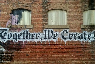 A brick wall with the words ‘Together We Create’ on it