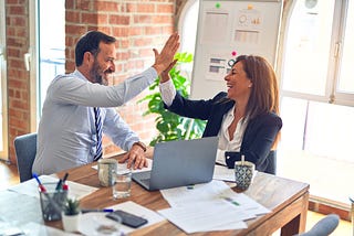 A man and a woman are seen celebrating a successful piece of work.