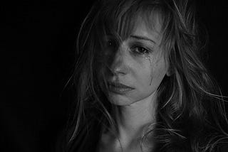 A black and white closeup photo of a woman crying