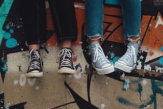 An image of two teenagers sitting on a wall.