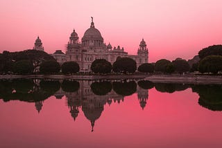 Image of Victoria Memorial in Kolkata, India at sunset with a red sky in the background reflecting red off the water