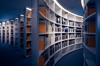 Foto de várias estantes de livros, na cor branca.
