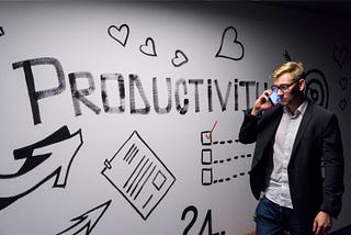 A man walking by a wall with the word productivity written on it.