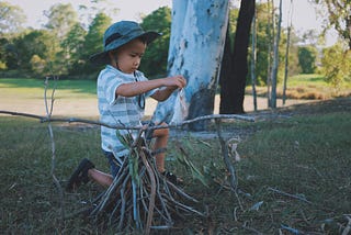 photo of child building something outside with sticks