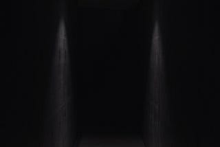 A dark hallway, lit by a solitary ceiling lamp.