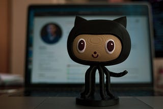 A wooden action figure from the github logo on a laptop