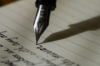 Black quill pen writing in a notebook
