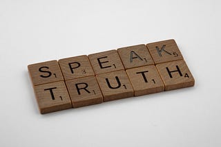 Scrabble tiles spelling out “SPEAK TRUTH”