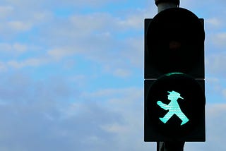 Photo of the green for “go” state on a German pedestrian signal from former East Germany. It shows the outline of a man in a hat.