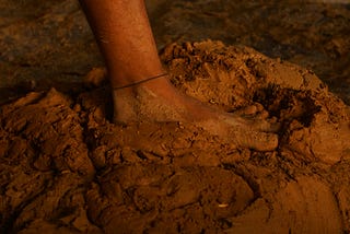 A bare foot pressing down into a pile of dirt