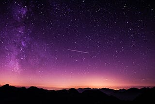 A view of pink-lavendar-blue galaxies and stars from a black Earth.