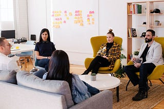 Three young women and two men sitting during a team meeting