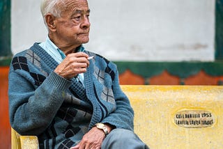 An Elderly person peacefully reflecting in nature, golden hour lighting, soft focus, calm atmosphere, aging gracefully