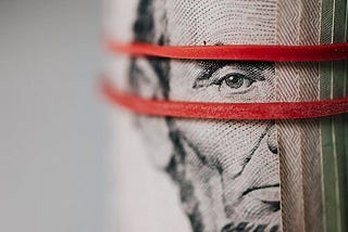 Roll of American dollar banknotes tightened with band — courtesy, pexels.com