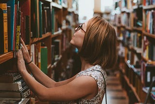Woman looking through bookshelves in a bookstore.