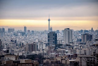 A photo centered on a tall tower in Tehran with a few high-rise buildings of perhaps 30 stories.
