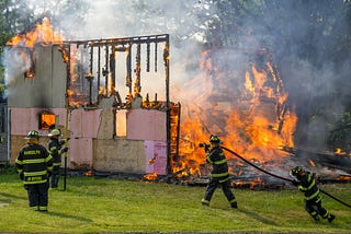 Fire fighters controlling a house on fire. The image is evocative of my childhood memory of watching the house next to us in Punjab on fire.