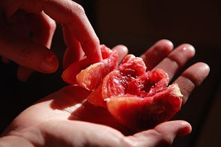 hands gently touching a sliced grapefruit segment