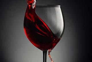 Glass of red wine being artistically poured
