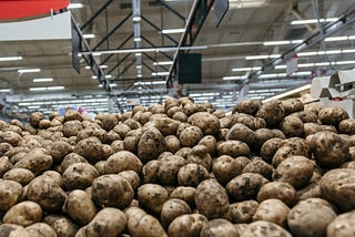 The picture shows a large pile of brown potatoes.