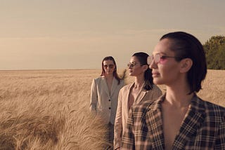Three women stand on a bright wide horizon