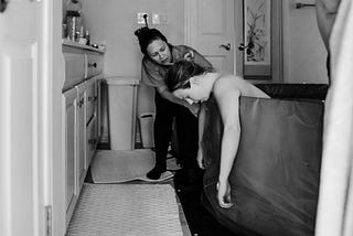 A pregnant woman lies in a tub during labor.