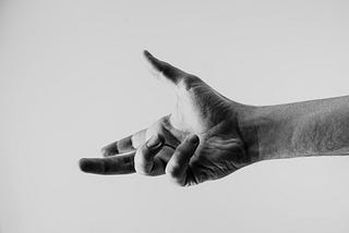 An outstretched hand, thumb pointing up. Forefinger and third digit stretched forward. Fourth and fifth digit curled over the palm