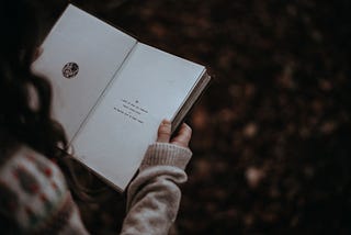 A girl reads the first page of a book.