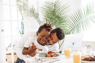 Father and daughter joyfully sharing a breakfast meal.
