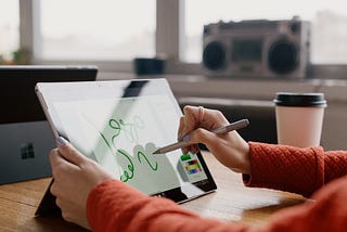 This image shows someone writing on an ipad on her desk.