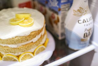 A lemon layer cake on a shelf in a fridge next to creamer