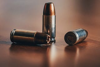 Close-up of three rounds of 9 mm hollow point lay randomly on a table top.