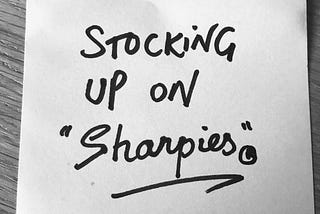 Black and white image of a Post-It with ‘Stocking up on Sharpies’ written in black marker