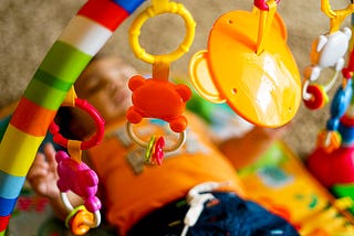 Baby surrounded by brightly colored toys.