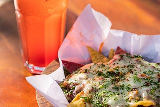 A plate of nachos and a beverage