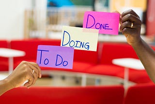 A picture with 3 sticky notes held up “To Do” “Doing” “Done”
