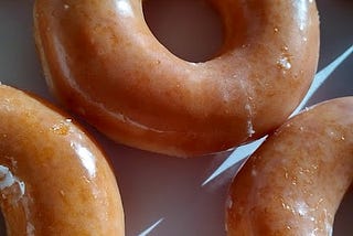 a close-up image of freshly glazed Krispy Kreme donuts in a box. Yum!