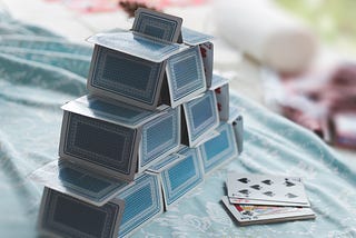 A house of blue backed cards with a few extra playing cards facing up next to them.