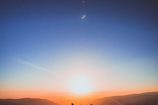 Three people standing in a sunrise landscape
