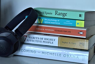 A picture of self-help books and a black headphone.