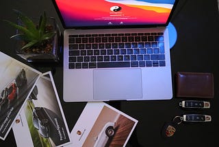 An open laptop surrounded by photos of cars