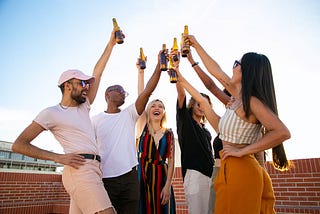 Six attractive young people cheers beers on an apartment rooftop.