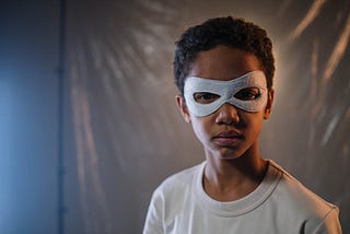 Boy in white shirt wearing eyemask looking towards the camera