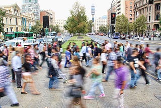 Blurred images of people crossing a busy sidewalk