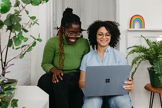 Two women looking at a laptop. Photo by Surface on Unsplash