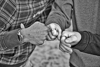 Black and white photo of three people bumping their fists.