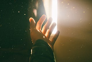 Extended hand observing the light passing through fingers.