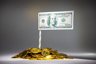A flag of a 100 dollar bill sitting atop a pile of gold coins.