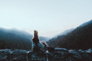 Girl sitting on rocks in the mountains.